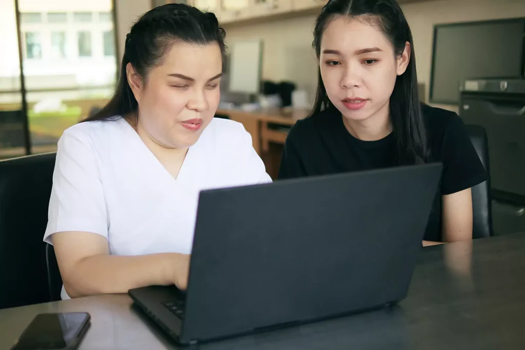 Blind disabled woman using laptop with support worker
